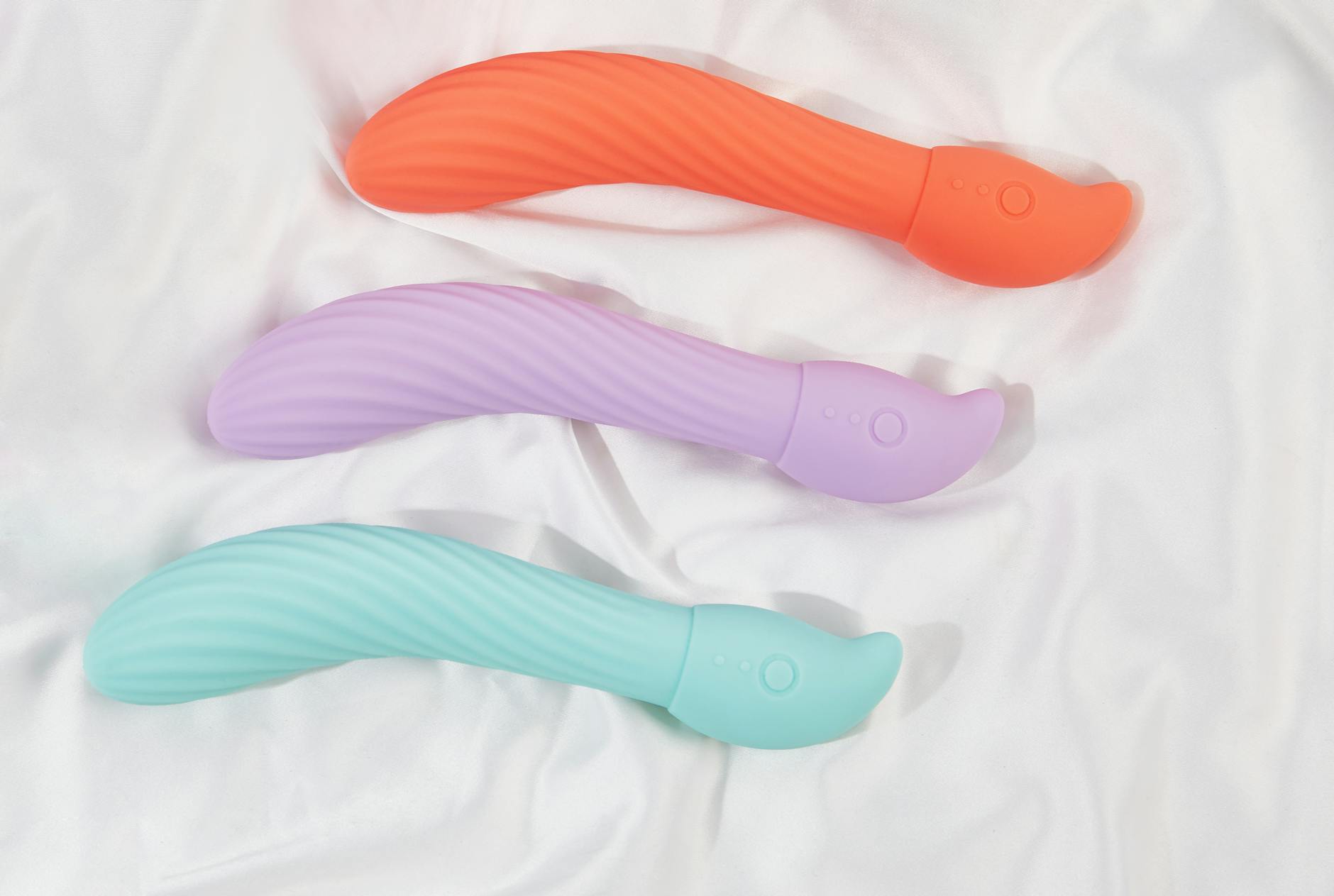 Hand holding a modern orange vibrator against a minimalist purple background, symbolizing vulnerability and intentional pleasure.