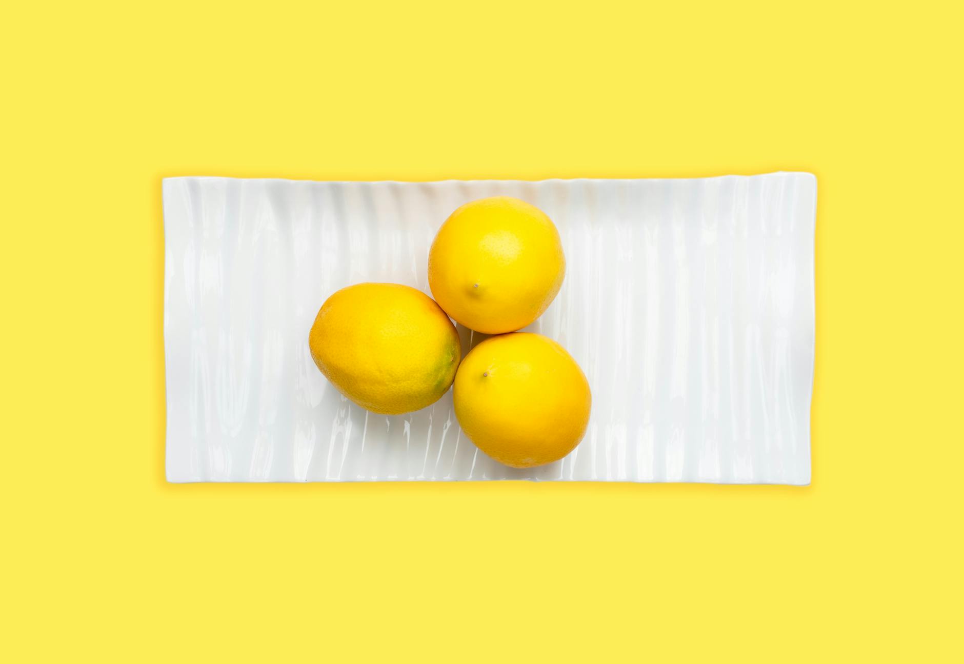 A blue vibrator surrounded by flowers and citrus slices on a bright yellow background