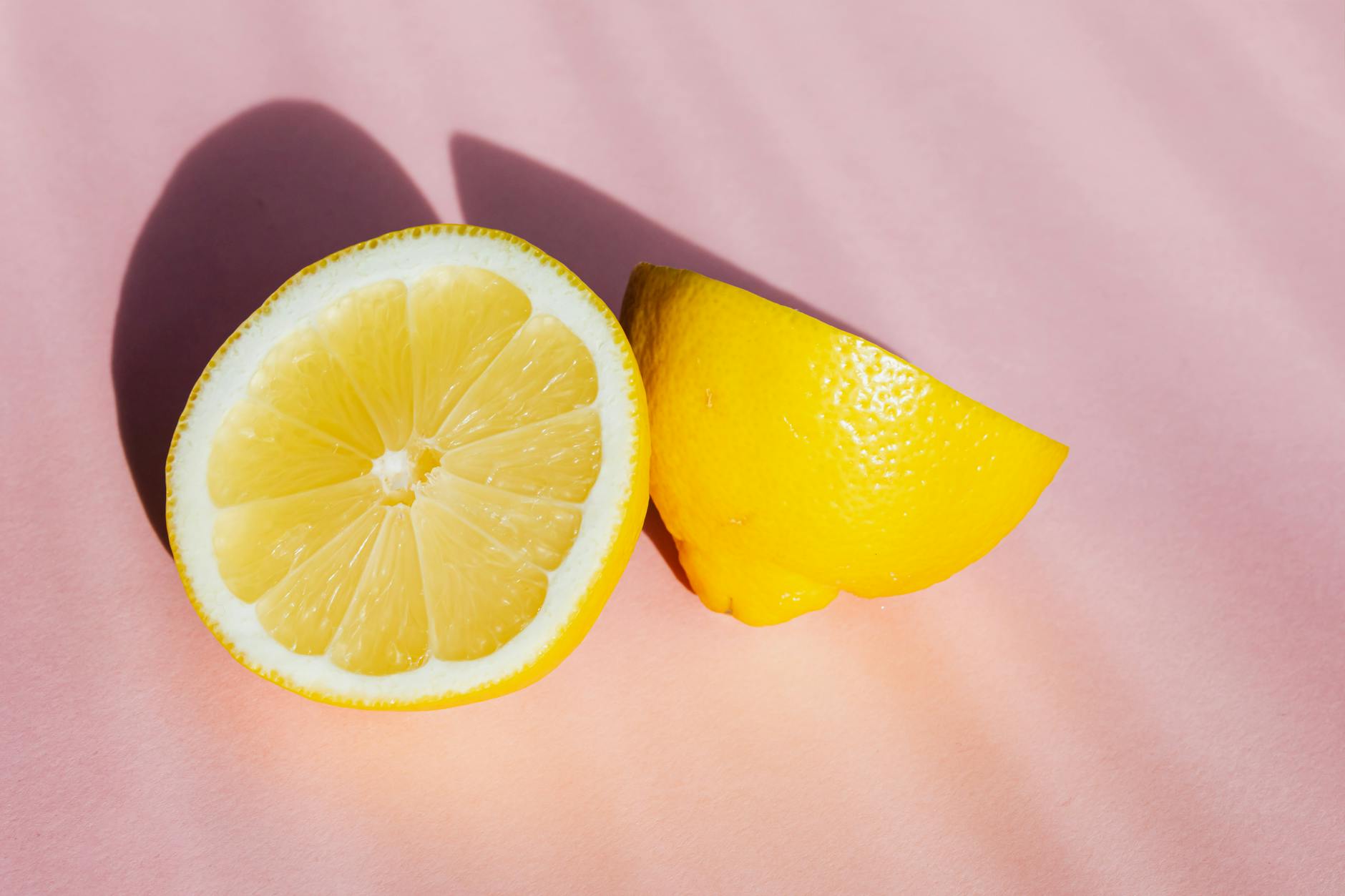 Fresh lemon halves on pink background in natural sunlight