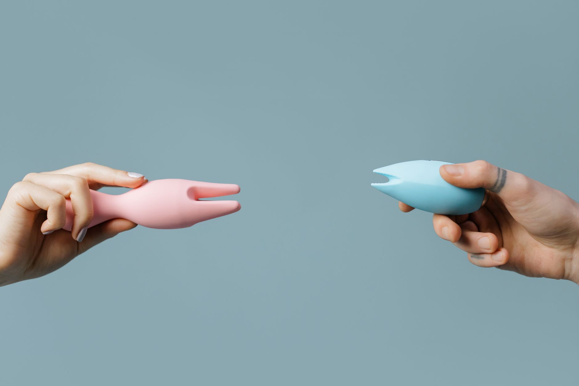 Hands holding colorful lemon vibrators against a pastel background