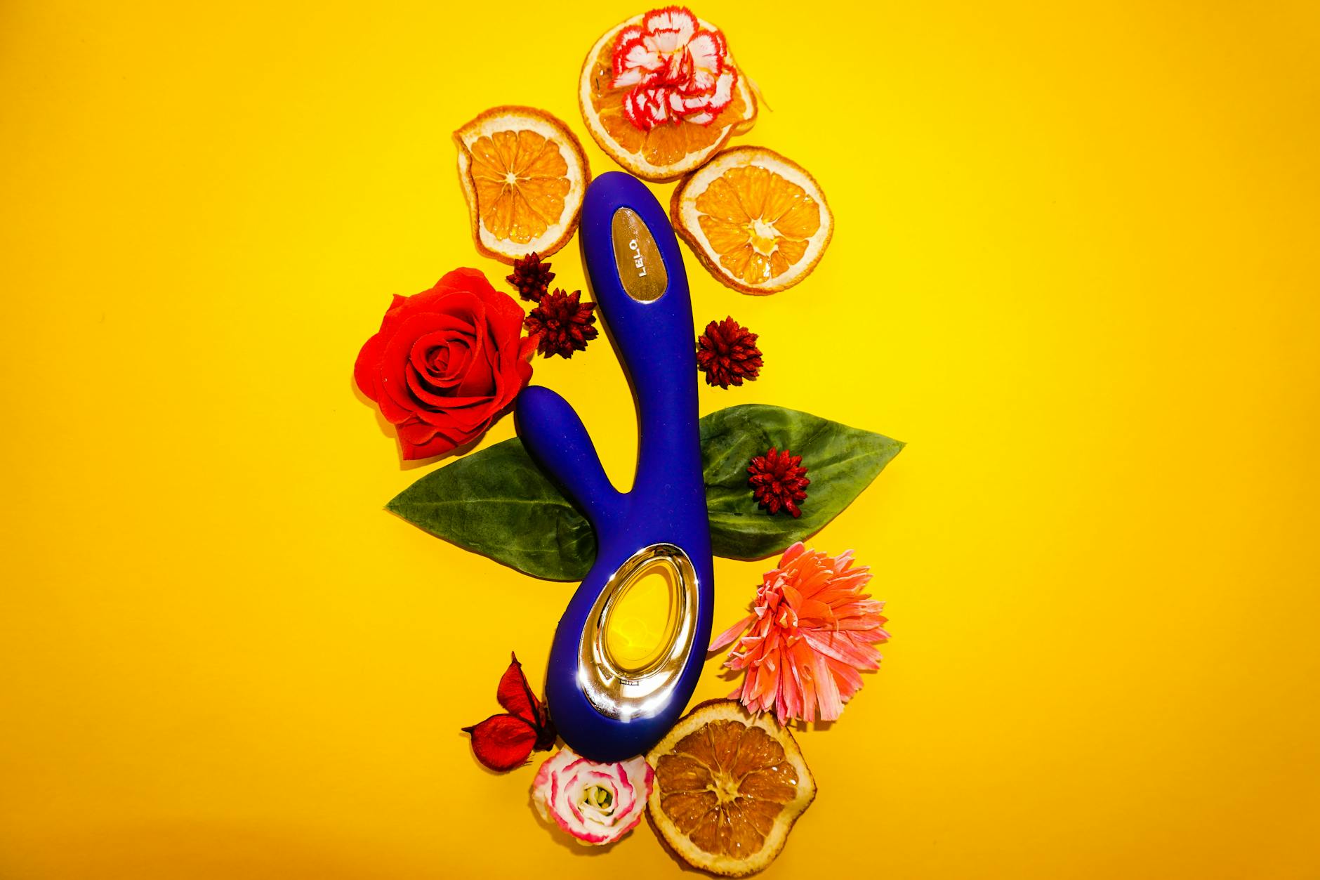 Colorful lemon vibrator surrounded by fresh flowers and citrus on a bright yellow background