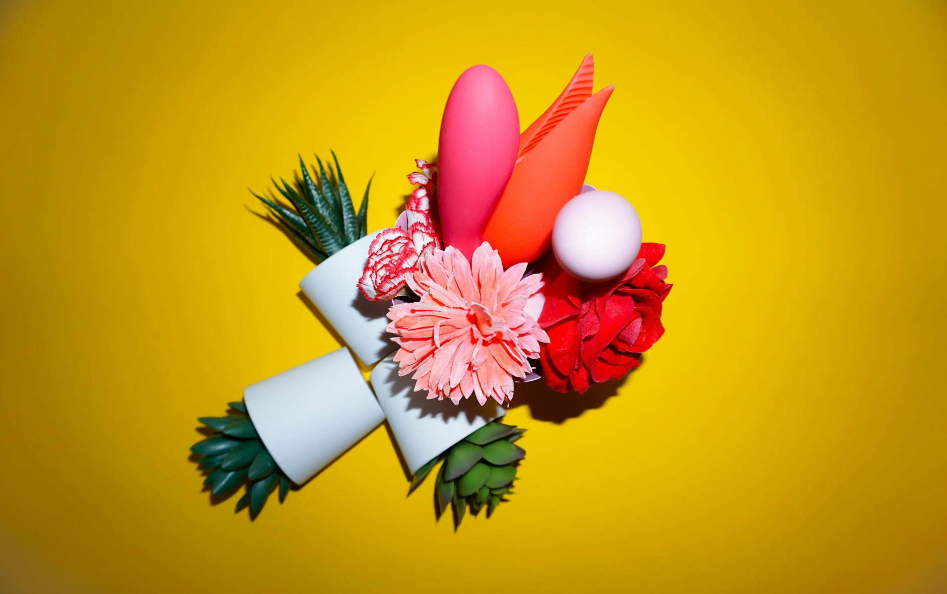 Hands holding vibrators in soft pastel tones against a neutral background